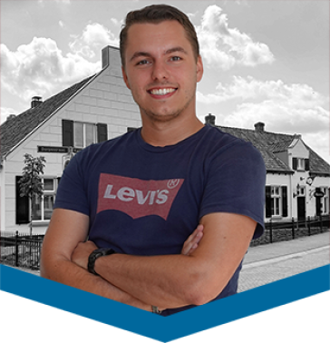 Franco. Franco staat op een foto met de armen over elkaar en lacht. Op de achtergrond is een wit puntig huis te zien. 